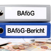 Zwei Aktenordner mit Aufschrift BAföG bzw. BAföG-Bericht liegen hinter Taschenrechner und Geldstücken